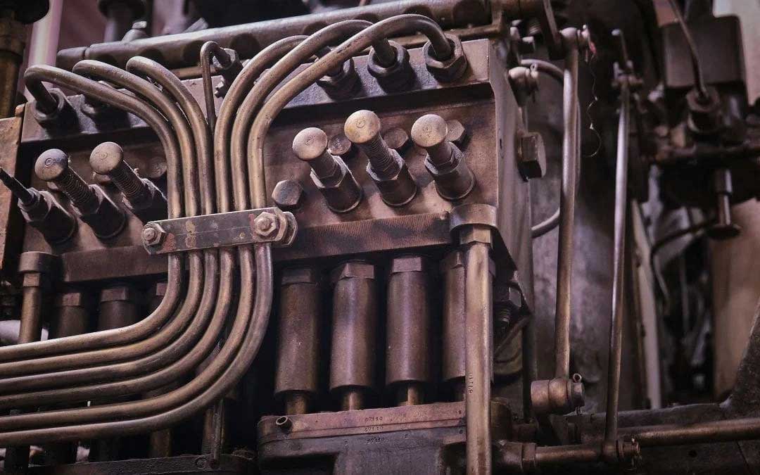 A series of curved steel pipes and valves connected to a block assembly in an engine, highlighting metal construction.